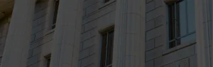 Close-up of a classical-style building facade with fluted columns, engraved stonework, and tall windows, symbolizing institutional authority, tradition, and architectural elegance.
